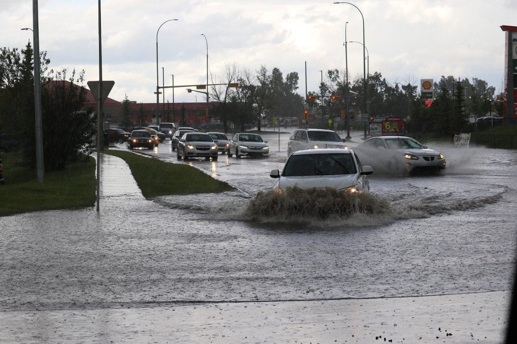 Cars driving down a flooded suburban road